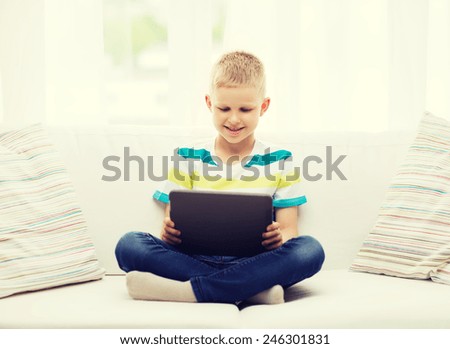 home, leisure and new technology concept - smiling little boy with tablet pc computer at home