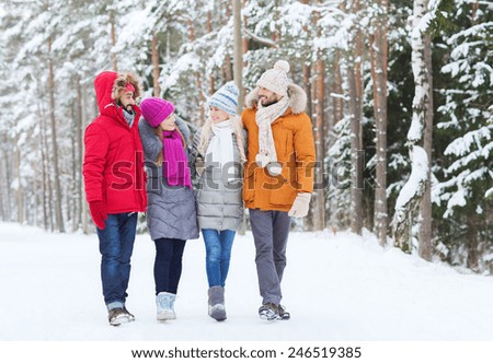 love, relationship, season, friendship and people concept - group of smiling men and women walking and talking in winter forest