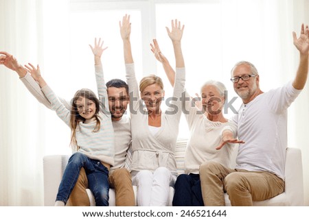 family, happiness, generation and people concept - happy family sitting on sofa and rising hands at home