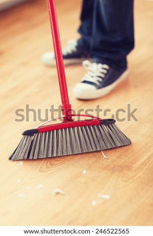 cleaning and home concept - close up of male brooming wooden floor