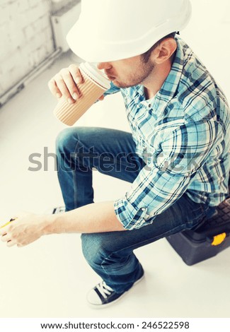 architect and home renovation concept - builder sitting on toolkit and drinking take away coffee