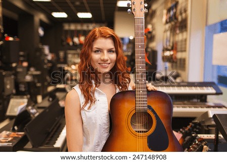 music, sale, people, musical instruments and entertainment concept - smiling female assistant or customer holding acoustic guitar at music store