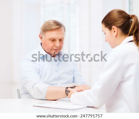 healthcare, elderly and medical concept - female doctor or nurse with male patient measuring blood pressure