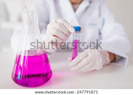 science, chemistry, medicine and people concept - close up of scientist with tube, pipette and flask making test or research in clinical laboratory