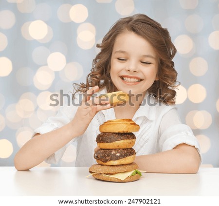 junk food, unhealthy eating, children and people concept happy smiling girl eating buns, donuts and burger over holidays lights background