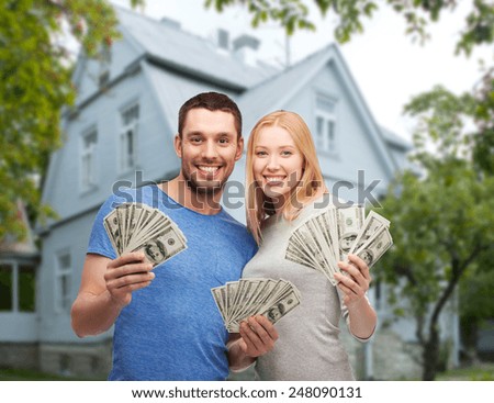 love, people, real estate, home and family concept - smiling couple showing dollar cash money over house background
