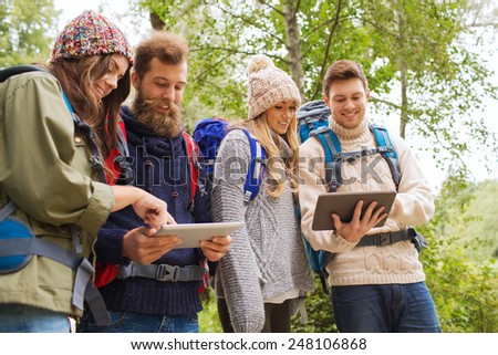 adventure, travel, tourism, hike and people concept - group of smiling friends with backpacks and tablet pc computers outdoors