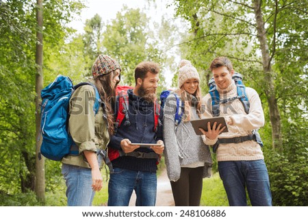 adventure, travel, tourism, hike and people concept - group of smiling friends with backpacks and tablet pc computers outdoors