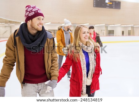 people, friendship, sport and leisure concept - happy friends on skating rink