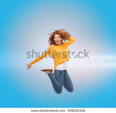 happiness, freedom, movement and people concept - smiling young woman jumping in air over blue laser background
