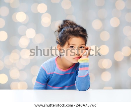 people, childhood and emotions concept - sad little girl over holidays lights background