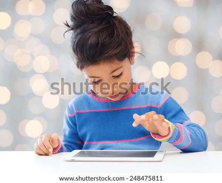 leisure, childhood, technology and people concept - little girl with tablet pc over holidays lights background