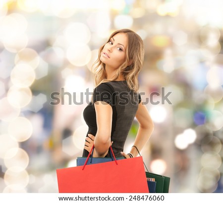 people, holidays and sale concept - young happy woman with shopping bags over lights background