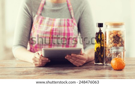 cooking, technology and home concept - closeup of woman reading recipe from tablet pc computer