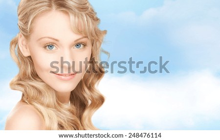 people, beauty, body and skin care concept - beautiful woman face and hands over blue sky background