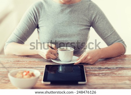 health, technology, internet, food and home concept - close up of woman drinking coffee and using tablet pc computer