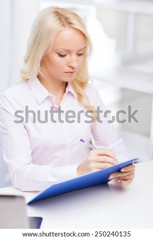 education, business and technology concept - smiling businesswoman or student with clipboard writing and taking notes in office