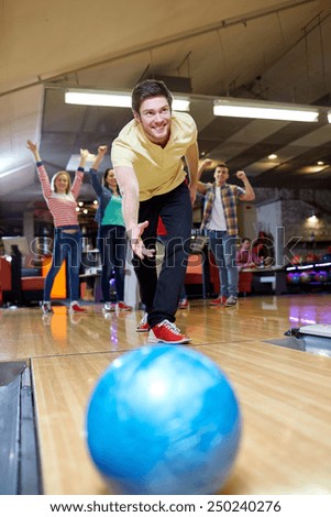 people, leisure, sport and entertainment concept - happy young man throwing ball in bowling club