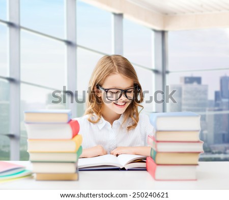 education, people, children and school concept - happy student girl in eyeglasses reading book at school over classroom background