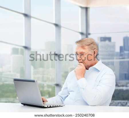 technology, oldness and people concept - senior man in eyeglasses with laptop over office window background