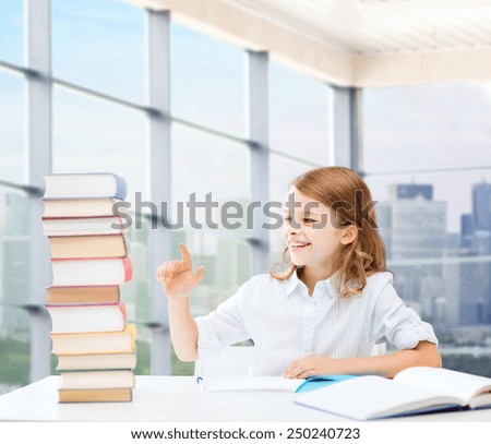 education, people, children and school concept - happy student girl sitting at table and counting books over classroom background