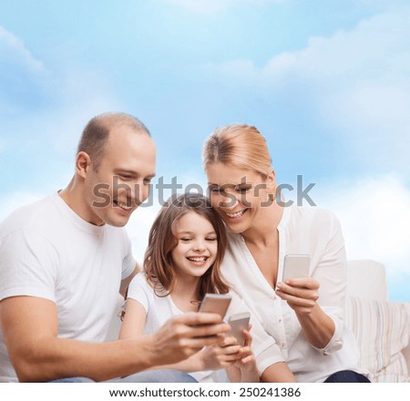 family, technology and people concept - smiling mother, father and little girl with smartphones over blue sky background