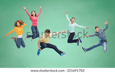 happiness, freedom, friendship, education and people concept - group of smiling teenagers jumping in air over green board background