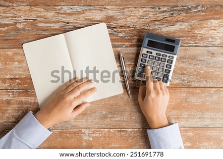 business, education, people and technology concept - close up of female hands with calculator, pen and notebook on table