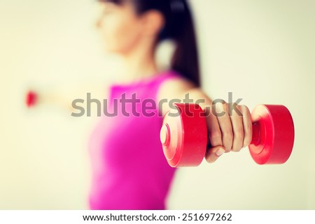 sport and recreation concept - sporty woman hands with light red dumbbells
