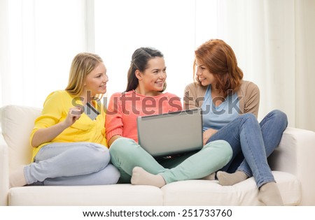 friendship, money, technology and internet concept - three smiling teenage girls with laptop computer and credit card at home
