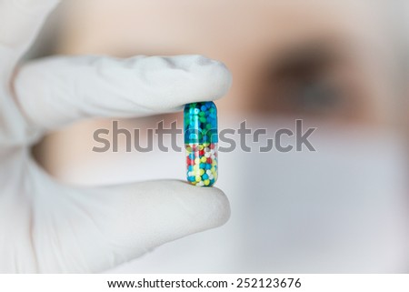 science, chemistry, biology, medicine and people concept - close up of young female scientist or doctor holding and showing pill in laboratory
