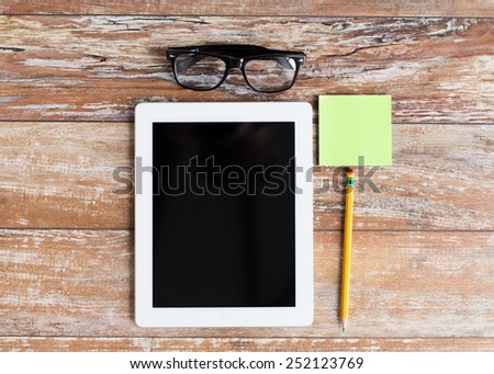 business, education, objects and technology concept - close up of tablet pc, eyeglasses and stickers with pencil on table