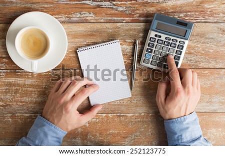 business, education, people and technology concept - close up of male hands with calculator, pen and notebook on table