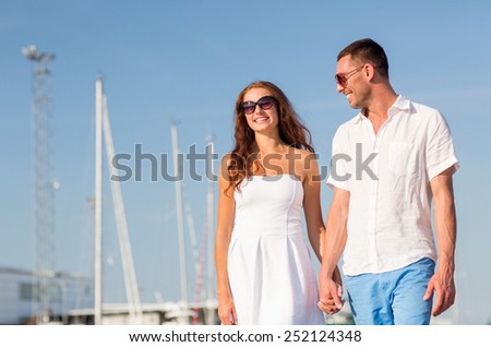love, travel, tourism, sailing, people and friendship concept - smiling couple wearing sunglasses walking at harbor