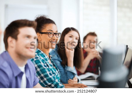 education concept - students with computers studying at school