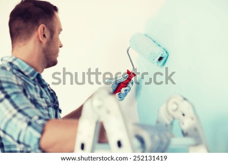 repair, building and home concept - close up of male in gloves holding painting roller