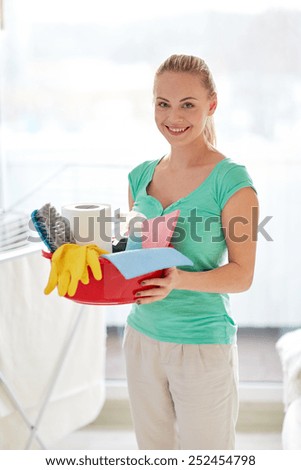 people, housework and housekeeping concept - happy woman holding cleaning stuff at home
