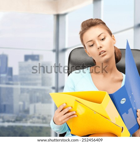 people, business and paperwork concept - young businesswoman with folders sitting on chair over office window background