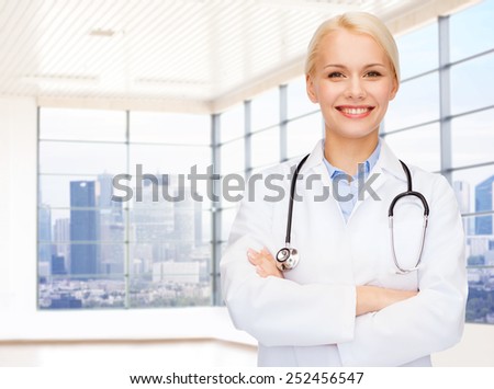 people, medicine and profession concept - smiling young female doctor over clinic background
