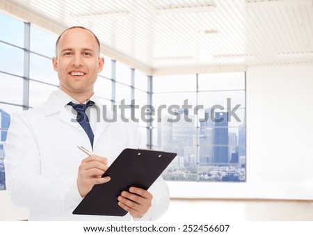 medicine, profession, people and healthcare concept - smiling male doctor with clipboard writing prescription over clinic background