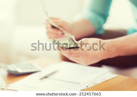 savings, finances, economy and home concept - close up of man with calculator counting money and making notes at home