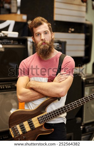 music, sale, people, musical instruments and entertainment concept - male musician or customer with beard playing bass guitar guitar at music store
