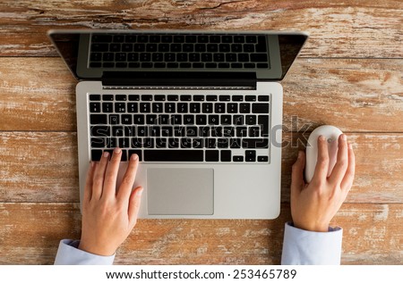 business, education, people and technology concept - close up of female hands with laptop and computer mouse on table