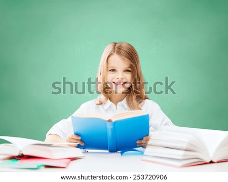 education, people, children and school concept - happy student girl reading book at school over green chalk board background
