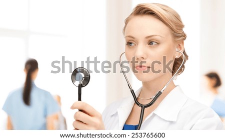 people, medicine, equipment and profession concept - young female doctor with stethoscope over hospital background