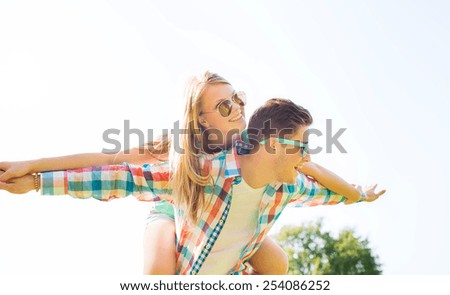 holidays, vacation, love and friendship concept - smiling couple having fun in park