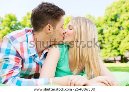 holidays, vacation, love and friendship concept - smiling couple kissing in park