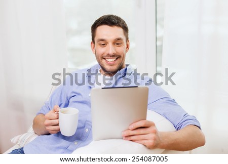 technology, people and leisure concept - handsome man with tablet pc computer and cup drinking coffee or tea at home