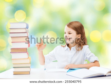 education, people, children and school concept - happy student girl sitting at table and counting books over green lights background