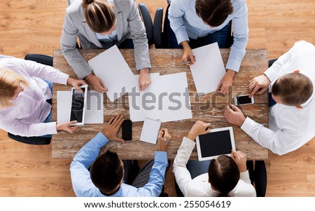 business, people and team work concept - close up of creative team with papers and gadgets meeting in office